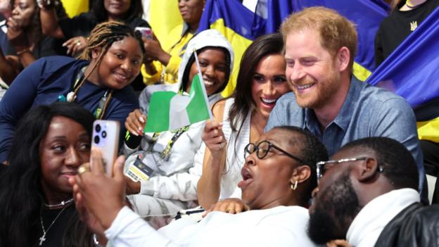 Prince Harry and Meghan Markle at the Invictus Games sitting with Nigeria fans
